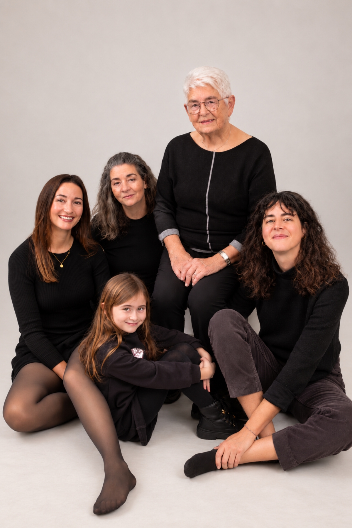 Fünf Frauen aus mehreren Generationen sitzen gemeinsam für ein Familienportrait im Fotostudio.
